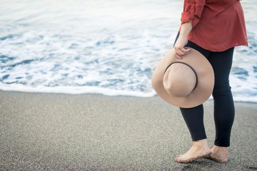 Frau mit Sommerhut barfu0 am Strand